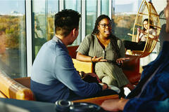 Two people having a conversation while sitting down in a lounge environment.