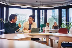 2 males having a discussion at a table with tablet in front of them